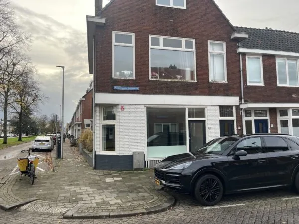 Straatbeeld van de Burgemeester Smitsstraat met geparkeerde auto's en een bakfiets op de stoep bij een hoekpand.